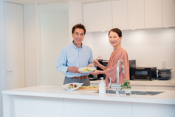 キッチンで一緒にクッキングを楽しむシニアの夫婦