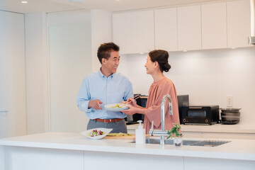 キッチンで一緒にクッキングを楽しむシニアの夫婦