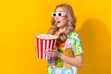 Photo of speechless impressed girl dressed colorful t-shirt hold popcorn staring at empty space isolated on yellow color background