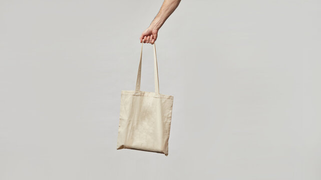 Cloth bag in hand on light background. Bag shoper in the hand