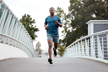 Black man, fitness and running on bridge in city for cardio exercise, workout or training outdoors. Fit, active and sporty African male person, athlete or runner exercising on a run in an urban town