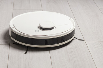 A robot vacuum cleaner at home on the floor.Helper at home. Lifestyle.