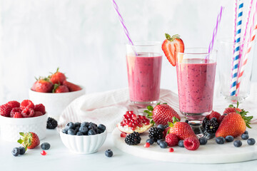 Glasses of mixed berry smoothie surrounded by berries.