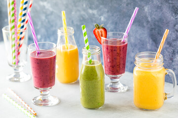 Refreshing healthy fruit smoothies with colourful straws.