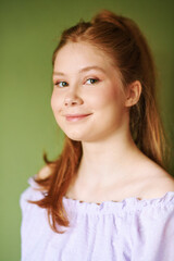 Beauty portrait of pretty young 15 - 16 year old red-haired teeenage girl wearing purple dress...