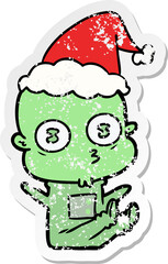 hand drawn distressed sticker cartoon of a weird bald spaceman wearing santa hat