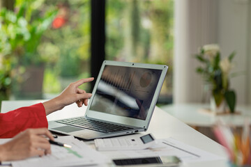 Fototapeta premium Asian businesswoman analyzes reports pointing to graphs, holding pens using laptops, business contacts, consulting to plan, financial statements, remote pictures.