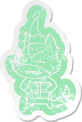 quirky cartoon distressed sticker of a wolf with a gift wearing santa hat