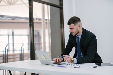 A caucasian male using laptop working at office. Car salesman planning to manage transportation...