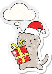 cute cartoon cat carrying christmas present with thought bubble as a distressed worn sticker