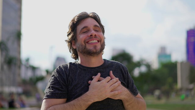 Exultant Young Man Expressing Hope and Faith with Uplifted Arms Celebrating Triumph Outdoors in the Park