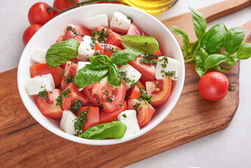 Fresh Italian salad antipasto called caprese with buffalo mozzarella, sliced tomatoes and basil with olive oil. Ingredients for vegetarian caprese salad. Italian food. top view. Rustic style.