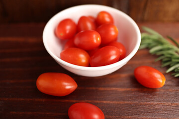 Cherry tomatoes in cup and on wooden table close up (spot focus)