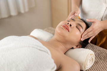 Obraz na płótnie Canvas Beautiful young Asian woman getting massage in spa environment, traditional aromatherapy and beauty therapy, close-up photo.