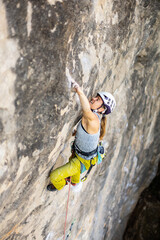 woman climbing big walls in the mountains, doing sports, striving hard for her goals without fear...