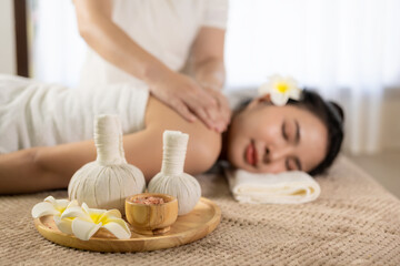 Fototapeta na wymiar Beautiful young Asian woman getting massage in spa environment, traditional aromatherapy and beauty therapy, close-up photo.
