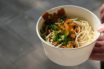 close up hand hold a bowl of Hot dry noodles. Traditional food in Wuhan, Hubei, China