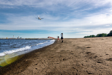 Fototapeta na wymiar 東京の城南島海浜公園で飛行機の写真を撮る少女たち