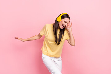 Photo of cool charming lady wear yellow t-shirt listen songs earphones dancing having fun isolated pink color background