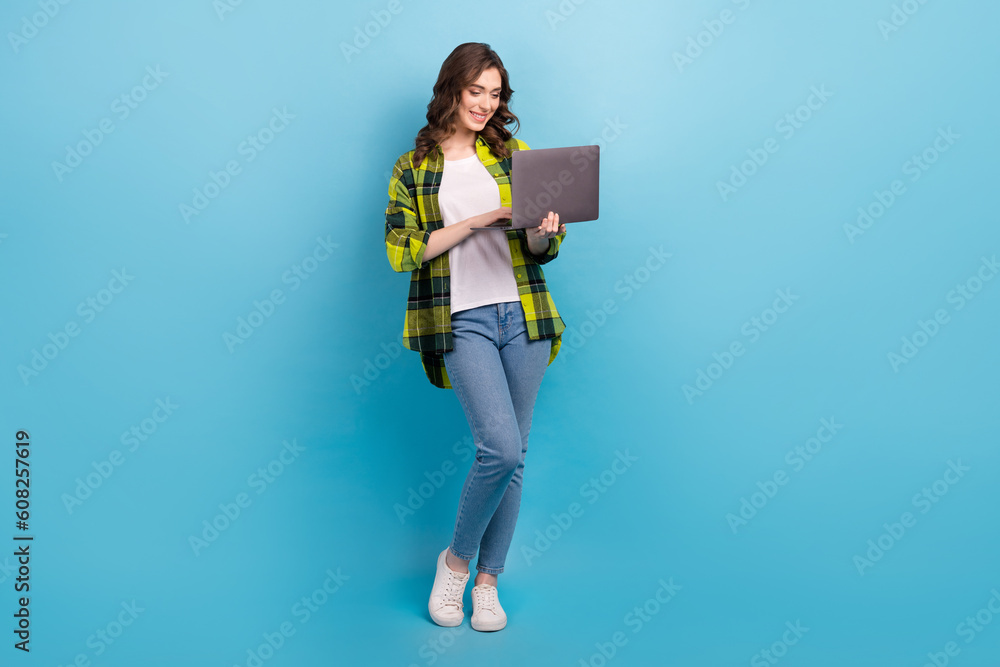 Poster full length photo of positive nice person use wireless netbook networking isolated on blue color bac