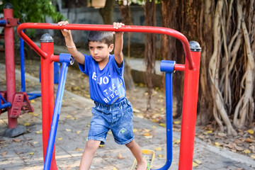 Fototapeta na wymiar Asian boy doing routine exercise in society park during the morning time. Cute little kid exercise and gym to keep himself fit for life. Child's exercise outdoor shoot