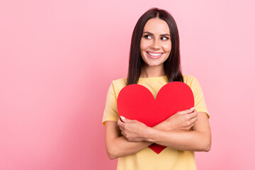 Photo of excited dreamy lady wear yellow t-shirt hugging big heart looking empty space isolated pink color background