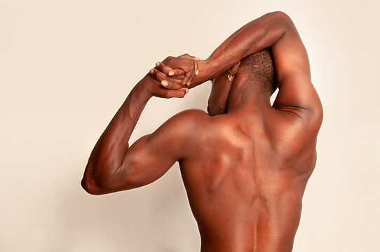Muscular black man stretching arms in studio