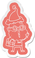quirky cartoon  sticker of a joyful man with beard and parcel under arm wearing santa hat