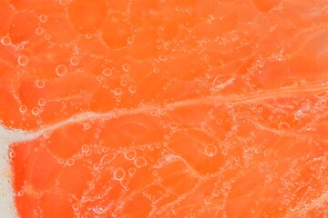 Close-up of a grapefruit slice in liquid with bubbles. Slice of ripe grapefruit in water. Close-up...