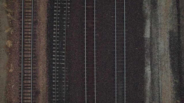 Birds eye view drone shot and aerial view of railroad train tracks on cloudy, winter day in cold weather and dirt