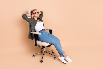 Full length photo of dreamy cute lady dressed khaki shirt arms behind head empty space isolated beige color background