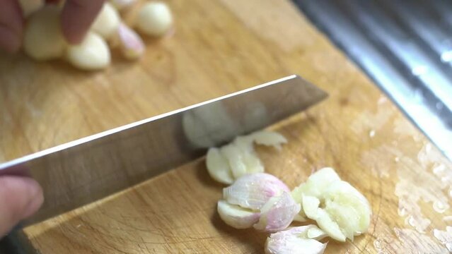 The chef peeling the garlic, The chef stirs the minced garlic with olive oil in a pan. Ingredients for cooking  in the kitchen.