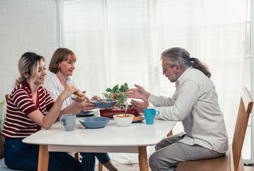 Members of the family from multiple generations enjoy quality time together by eating, snacking, chatting, discussing, learning about each other's interests, and strengthening stronger relationships.