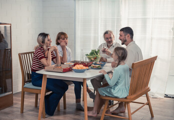 Members of the family from multiple generations enjoy quality time together by eating, snacking, chatting, discussing, learning about each other's interests, and strengthening stronger relationships.
