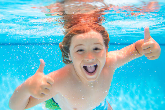Funny kids face underwater. Excited child swimming underwater in swimming pool. Funny kids boy play and swim in the sea water.