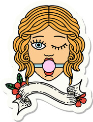 tattoo style sticker with banner of a winking female face wearing ball gag