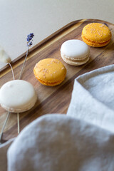 Four colorful macarons on a wooden plate and a linen napkin