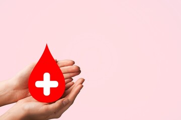 Obraz premium Hands holding red blood drop, donor day concept
