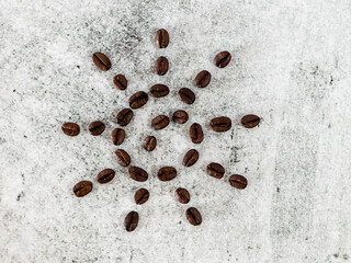Close shot of roasted coffee beans in sun shape on white background.