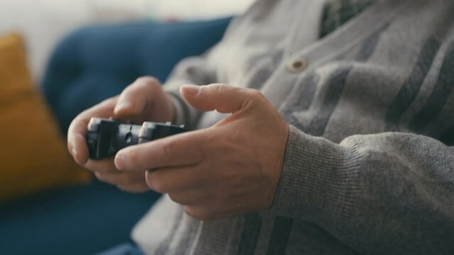Closeup of senior man playing video game using joystick, relaxation at home