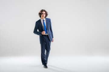 Full-length portrait of a handsome young man in a dark blue business suit on a white background.