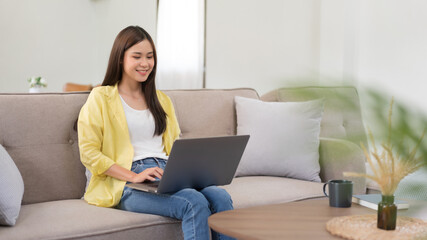Leisure activity concept, Young woman is chatting with friends on laptop while sitting on the couch