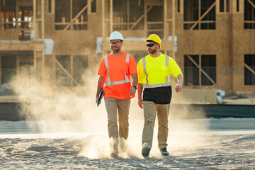 Builders on the job. Two builders in a hard hat at construction site. Men builders on construction sites. Hard hat builders helmet is a visible symbol of a safety and professionalism.