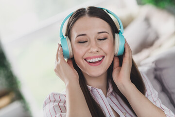 Photo of pretty cheerful young lady dressed striped shirt closed eyes enjoying songs headphones indoors house room