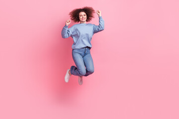 Full length photo of funky lucky lady wear blue sweatshirt jumping high rising fists empty space isolated pink color background