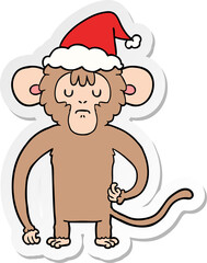 hand drawn sticker cartoon of a monkey scratching wearing santa hat