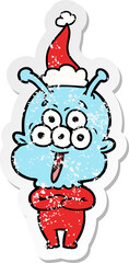 happy hand drawn distressed sticker cartoon of a alien wearing santa hat