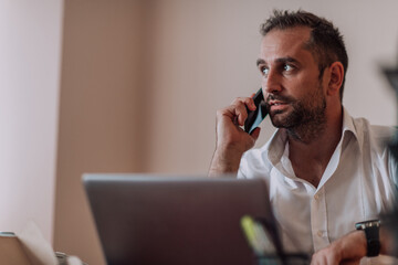 A businessman talking on his smartphone while seated in an office, showcasing his professional demeanor and active communication.