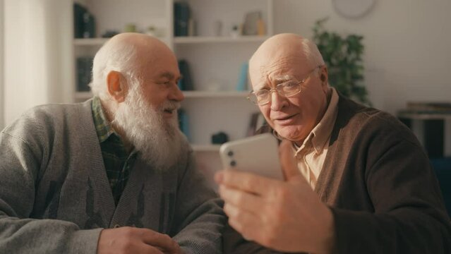 Two elderly buddies seeing some shocking content on smartphone, leisure time