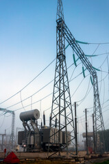 An electrical substation with transformers, equipment and high voltage pylons in the fog on an early spring morning.